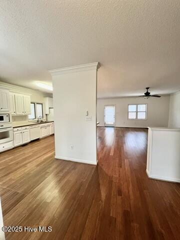 unfurnished living room featuring a textured ceiling, ceiling fan, ornamental molding, and hardwood / wood-style flooring