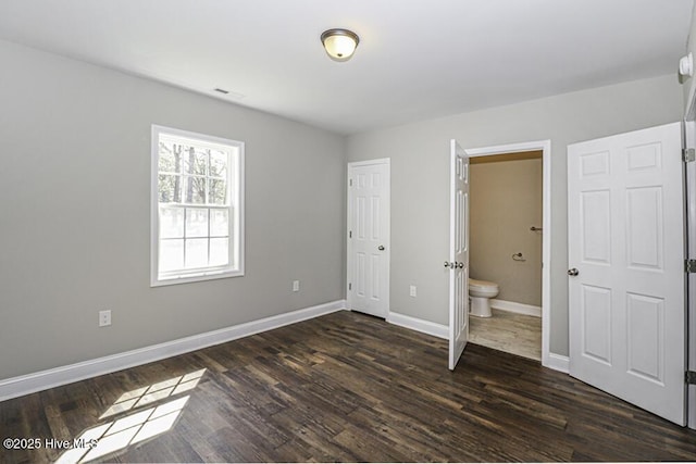 unfurnished bedroom featuring ensuite bath and dark hardwood / wood-style floors