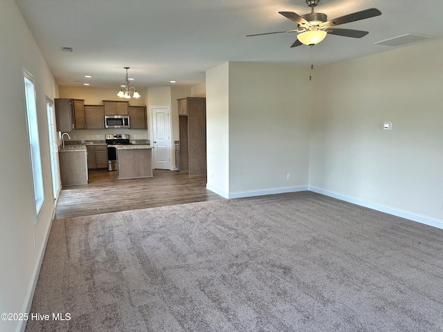 kitchen with appliances with stainless steel finishes, ceiling fan with notable chandelier, carpet floors, pendant lighting, and a center island