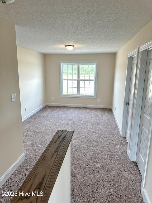 unfurnished room with light colored carpet and a textured ceiling