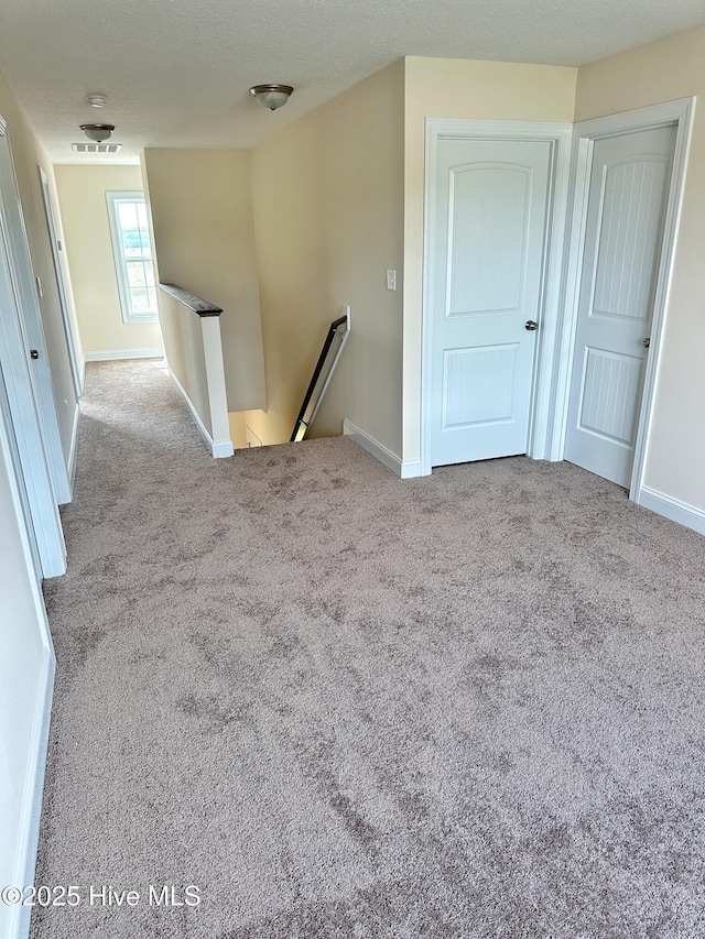 carpeted empty room with a textured ceiling