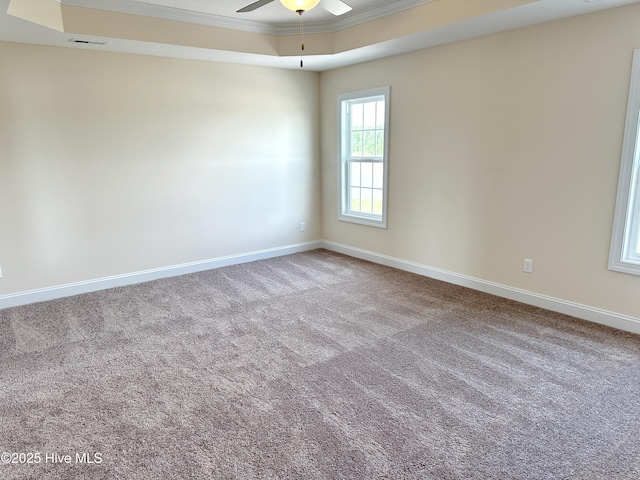 carpeted empty room with a tray ceiling, ceiling fan, and ornamental molding