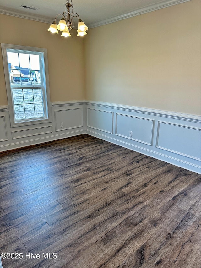 empty room featuring ornamental molding, dark wood-type flooring, and an inviting chandelier