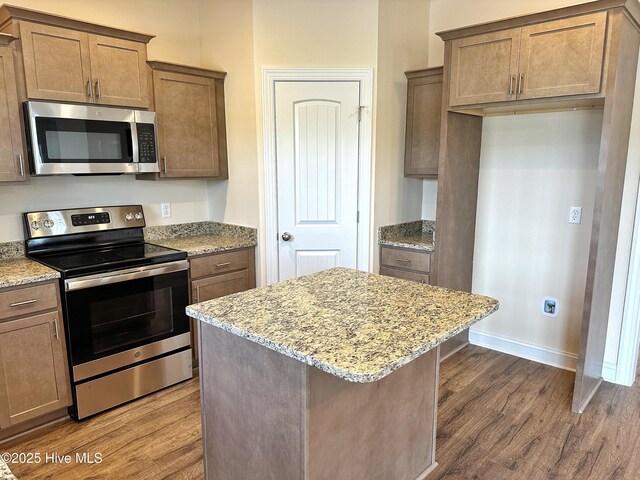 kitchen with a kitchen island, stainless steel appliances, light stone counters, and dark wood-type flooring