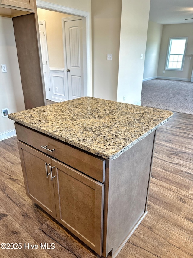 kitchen with light stone countertops, a kitchen island, and wood-type flooring