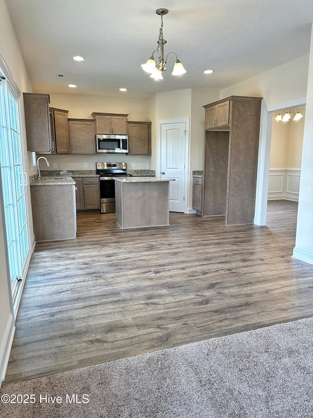 kitchen with a notable chandelier, a center island, wood-type flooring, and stainless steel appliances