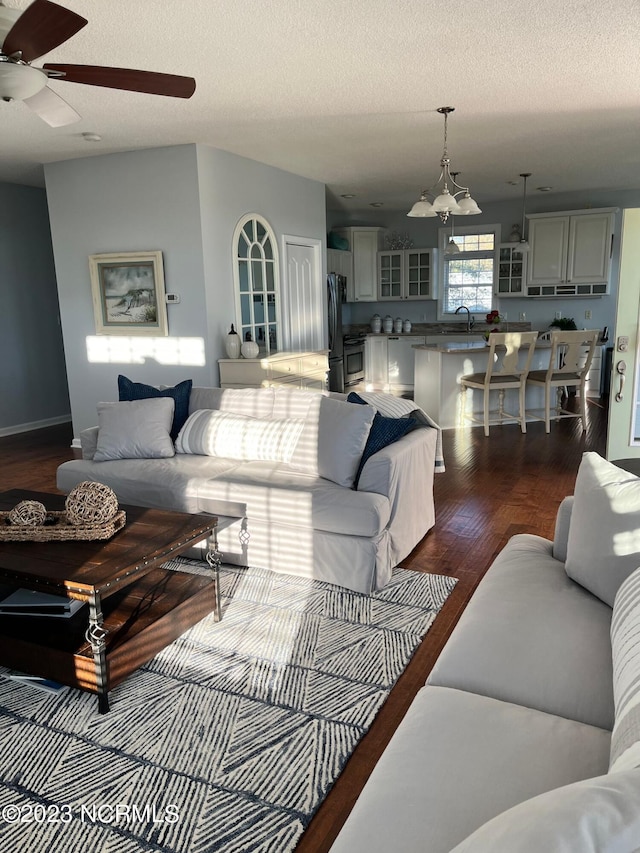 living room featuring ceiling fan, sink, a textured ceiling, and hardwood / wood-style flooring