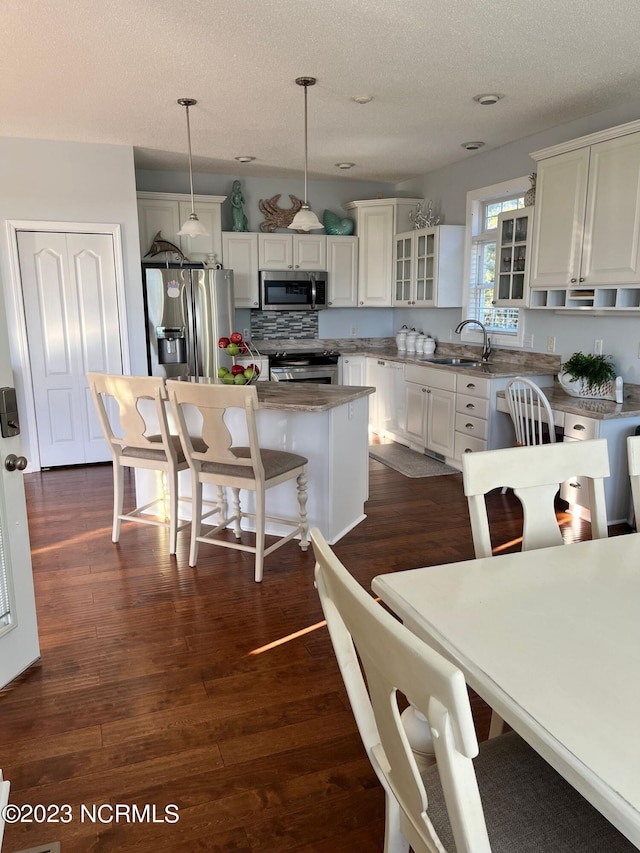 kitchen featuring pendant lighting, a center island, sink, tasteful backsplash, and stainless steel appliances