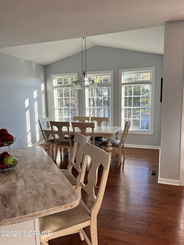 dining area with lofted ceiling, dark hardwood / wood-style floors, and a textured ceiling