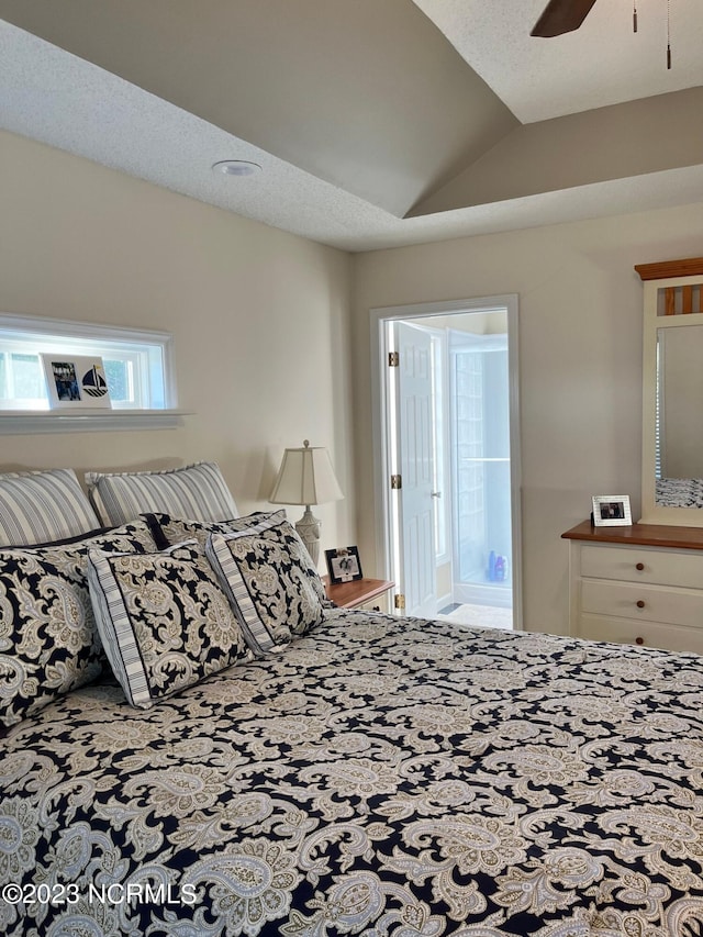 bedroom with a textured ceiling, ceiling fan, ensuite bathroom, and vaulted ceiling