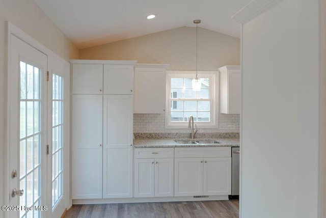 kitchen with tasteful backsplash, sink, white cabinets, and vaulted ceiling