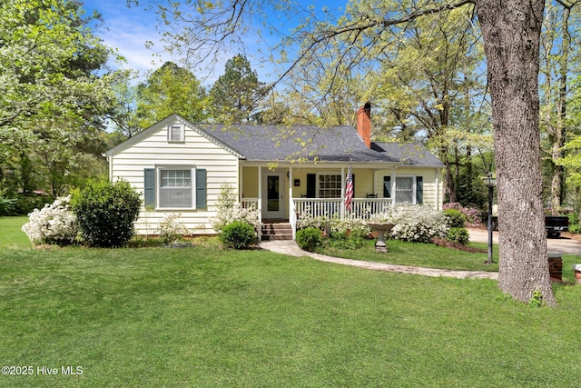 ranch-style house with roof with shingles, a front yard, a porch, and a chimney