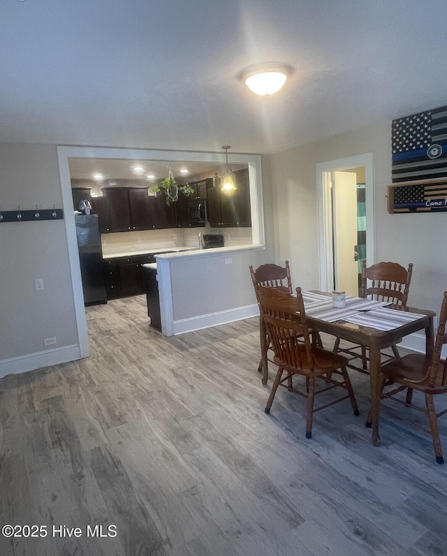 kitchen with hardwood / wood-style floors, pendant lighting, black refrigerator, and kitchen peninsula