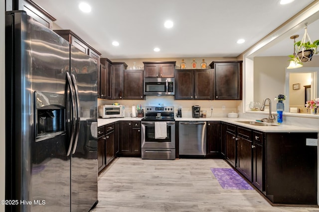 kitchen with a sink, light countertops, dark brown cabinetry, and stainless steel appliances