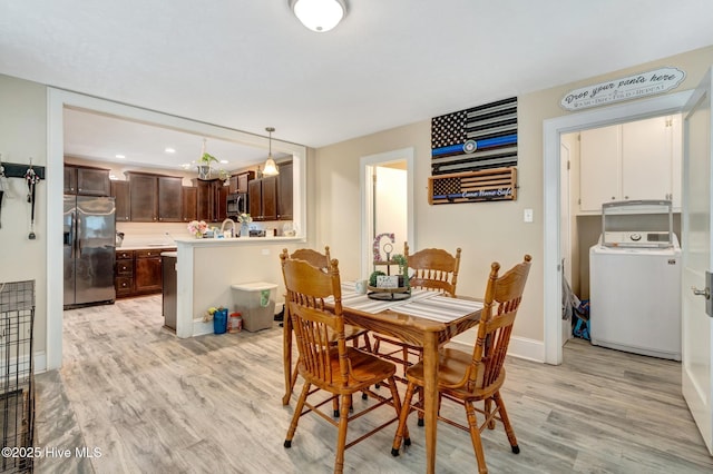 dining room with washer / clothes dryer, light wood-style floors, and baseboards