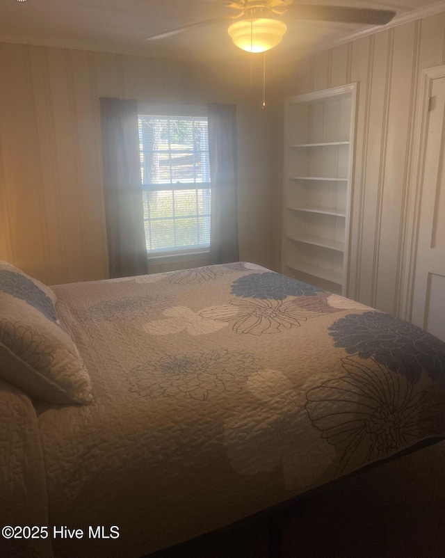 bedroom with ceiling fan and wooden walls