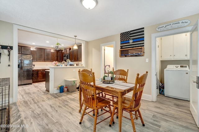 dining area featuring baseboards, washer / dryer, and light wood finished floors