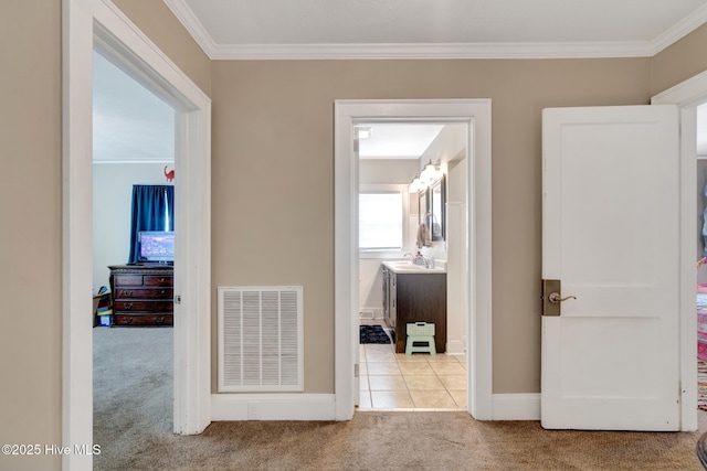 hall featuring crown molding, visible vents, baseboards, and carpet