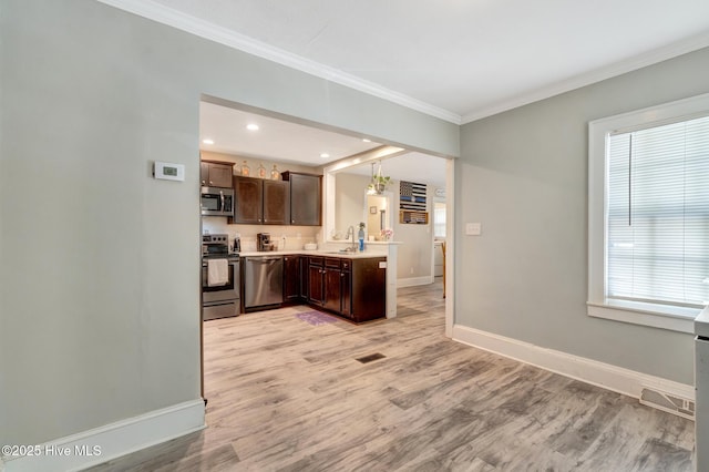 kitchen with dark brown cabinetry, baseboards, crown molding, stainless steel appliances, and a sink