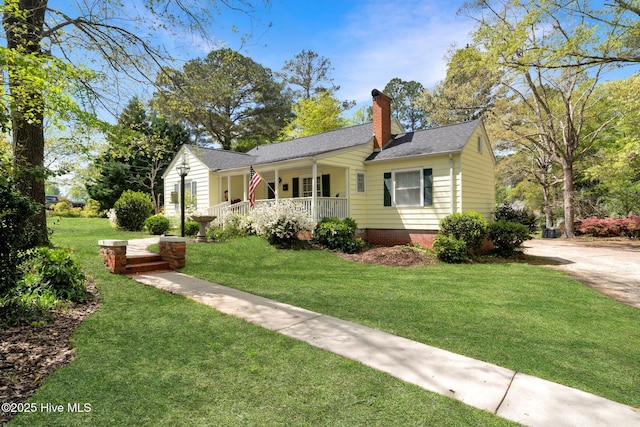 view of front facade with crawl space, a porch, roof with shingles, a front yard, and a chimney