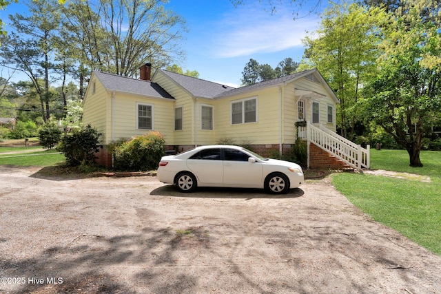 view of front facade featuring roof with shingles, a chimney, and a front lawn