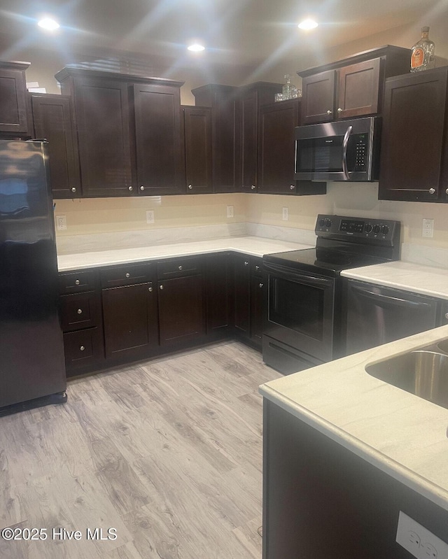 kitchen featuring dark brown cabinets, stainless steel appliances, and light wood-type flooring