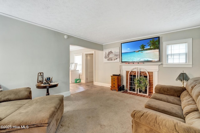 living room featuring baseboards, a fireplace, crown molding, carpet floors, and a textured ceiling
