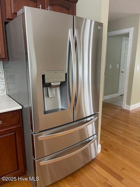 interior details featuring stainless steel fridge and light hardwood / wood-style flooring