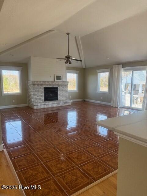 unfurnished living room with a fireplace, dark tile patterned floors, vaulted ceiling, and ceiling fan