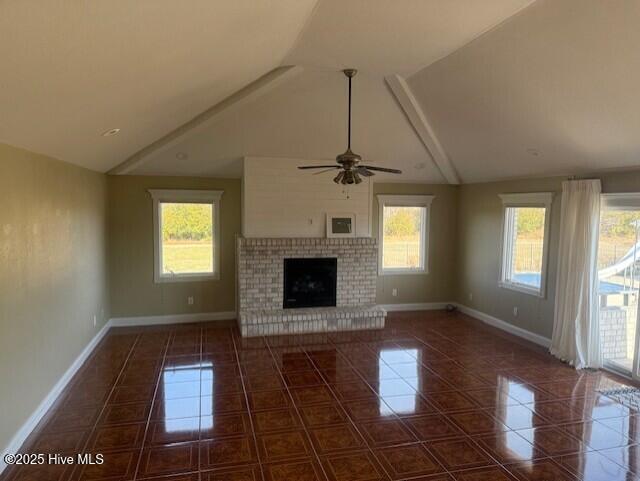 unfurnished living room with dark tile patterned flooring, ceiling fan, a fireplace, and vaulted ceiling