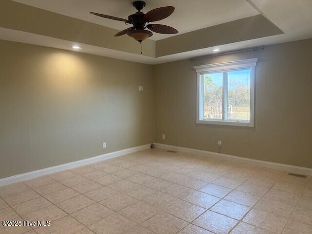 tiled spare room with a raised ceiling and ceiling fan