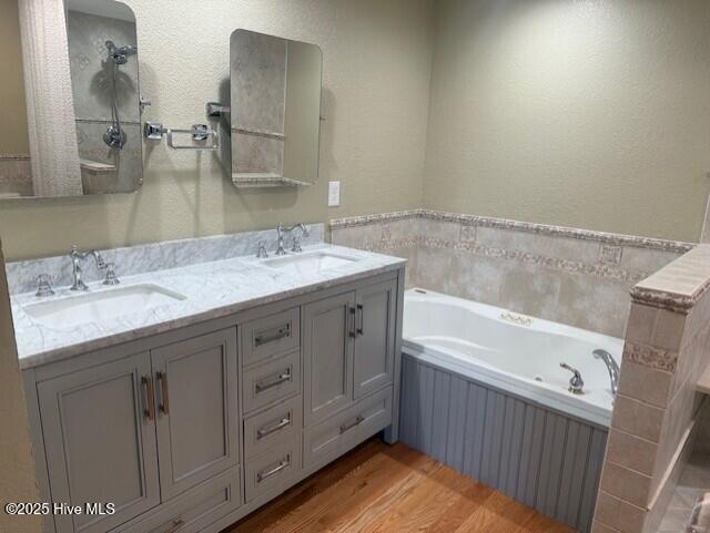 bathroom with a tub to relax in, hardwood / wood-style floors, and vanity