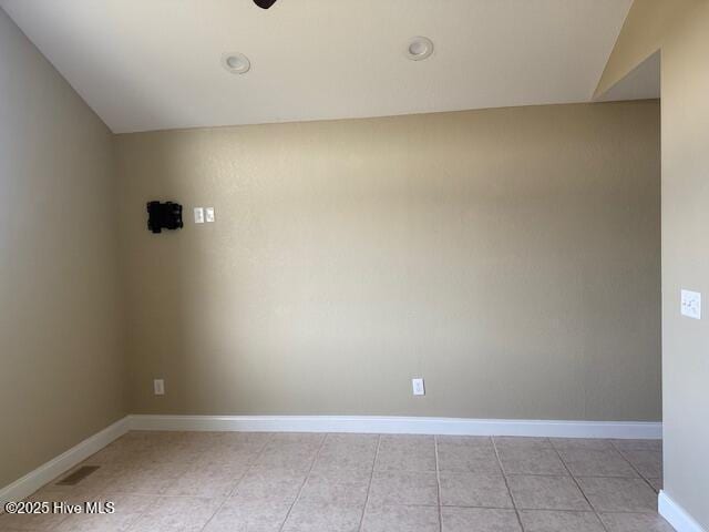 spare room with light tile patterned flooring and lofted ceiling