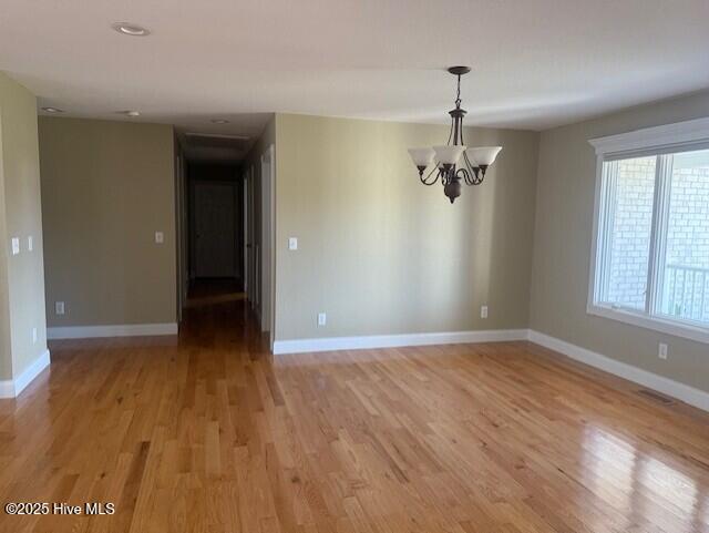 unfurnished room with light hardwood / wood-style flooring and an inviting chandelier