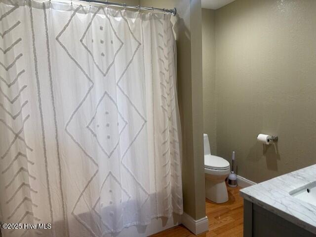 full bathroom featuring hardwood / wood-style floors, vanity, toilet, and shower / bathtub combination with curtain