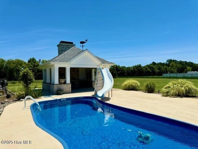 view of pool featuring a patio area, an outbuilding, and a water slide