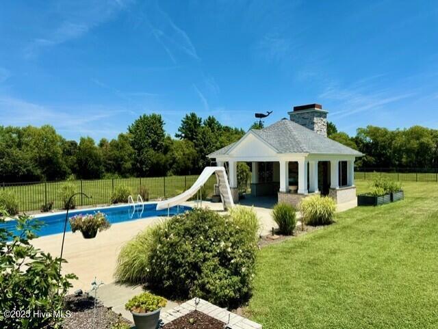 back of property featuring a fenced in pool and a lawn