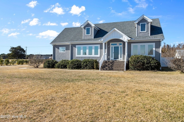 new england style home with a shingled roof and a front yard