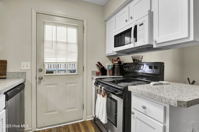 kitchen with stainless steel appliances, white cabinetry, and dark hardwood / wood-style floors