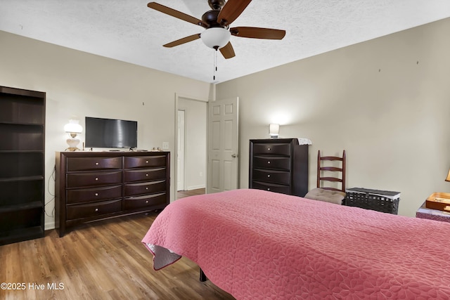 bedroom featuring ceiling fan, hardwood / wood-style floors, and a textured ceiling