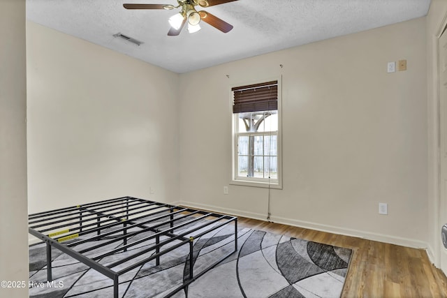 unfurnished bedroom with hardwood / wood-style flooring, ceiling fan, and a textured ceiling