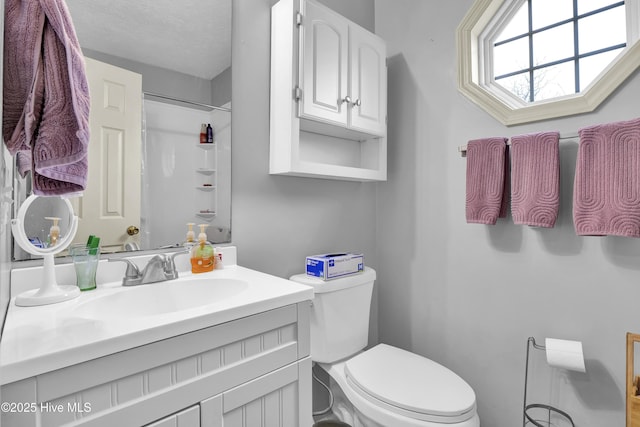 bathroom with vanity, toilet, and a shower