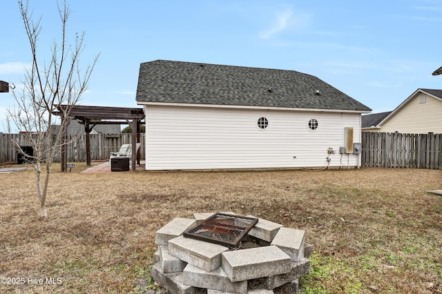 rear view of property with a lawn, a pergola, and an outdoor fire pit