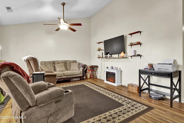 living room featuring ceiling fan, wood-type flooring, and vaulted ceiling