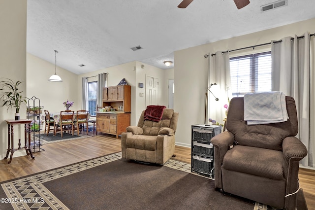 living room with a textured ceiling, hardwood / wood-style flooring, ceiling fan, and lofted ceiling