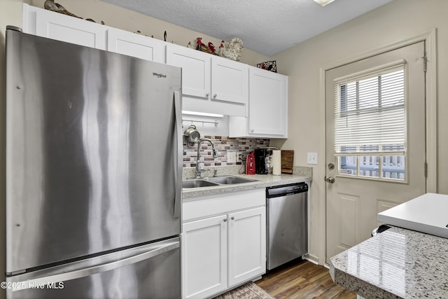 kitchen with white cabinetry, sink, stainless steel appliances, dark hardwood / wood-style flooring, and backsplash