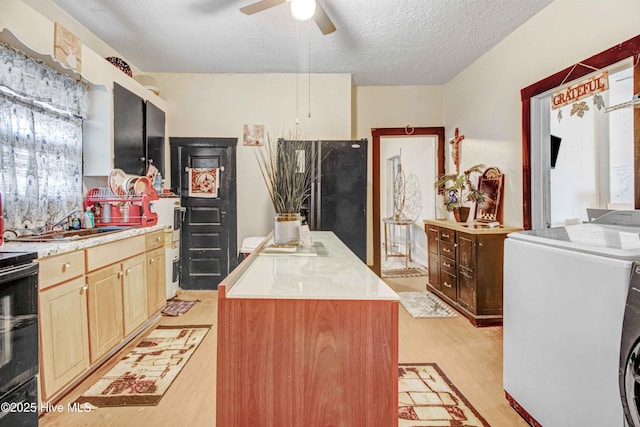 kitchen with washer / clothes dryer, a textured ceiling, ceiling fan, light hardwood / wood-style floors, and a kitchen island