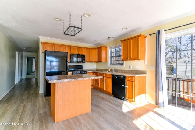 kitchen featuring sink, light hardwood / wood-style floors, a kitchen island, and black appliances