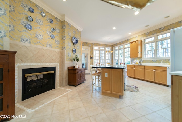 kitchen featuring pendant lighting, a center island, crown molding, a breakfast bar area, and a tiled fireplace