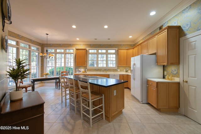 kitchen featuring ornamental molding, white appliances, pendant lighting, a notable chandelier, and a center island